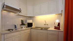 Una cucina compatta con mobili bianchi, un forno a microonde, un lavello e un pavimento a righe.