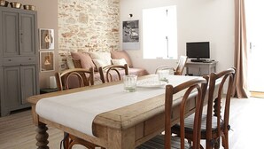 A dining area with a wooden table, chairs, and a stone wall.
