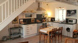 A kitchen with white cabinets, a dining table with chairs, a washing machine, and a staircase.