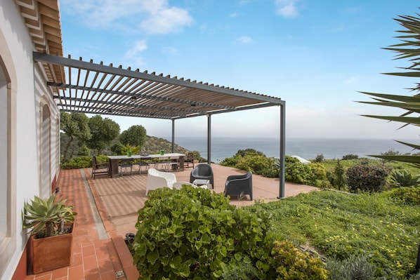 Une terrasse dotée d’une pergola, d’un espace salon extérieur et offrant une vue sur la mer.