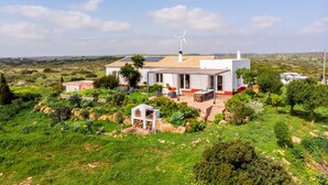 Una casa con un aerogenerador, paneles solares y un jardín.