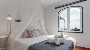 Un dormitorio con cama a dosel, una mesita de noche, una ventana con vistas y una toalla sobre la cama.