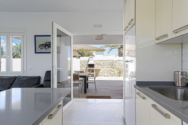 A modern kitchen with a dining area, a stone wall, and a view of the outside.