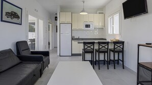 A modern kitchen with white cabinets, a microwave, and a dining area with a white table and four chairs. - Vacation Home "Rocamar" with Mountain View, Pool, Wi-Fi, A/C, Terrace & Garden (Barbate)