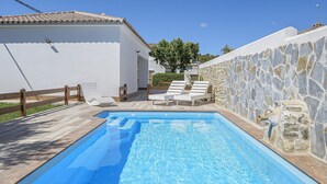 A swimming pool with a stone wall and wooden deck. - Vacation Home "Rocamar" with Mountain View, Pool, Wi-Fi, A/C, Terrace & Garden (Barbate)