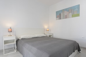 A bedroom with a bed, two bedside tables, and a wall-mounted painting.