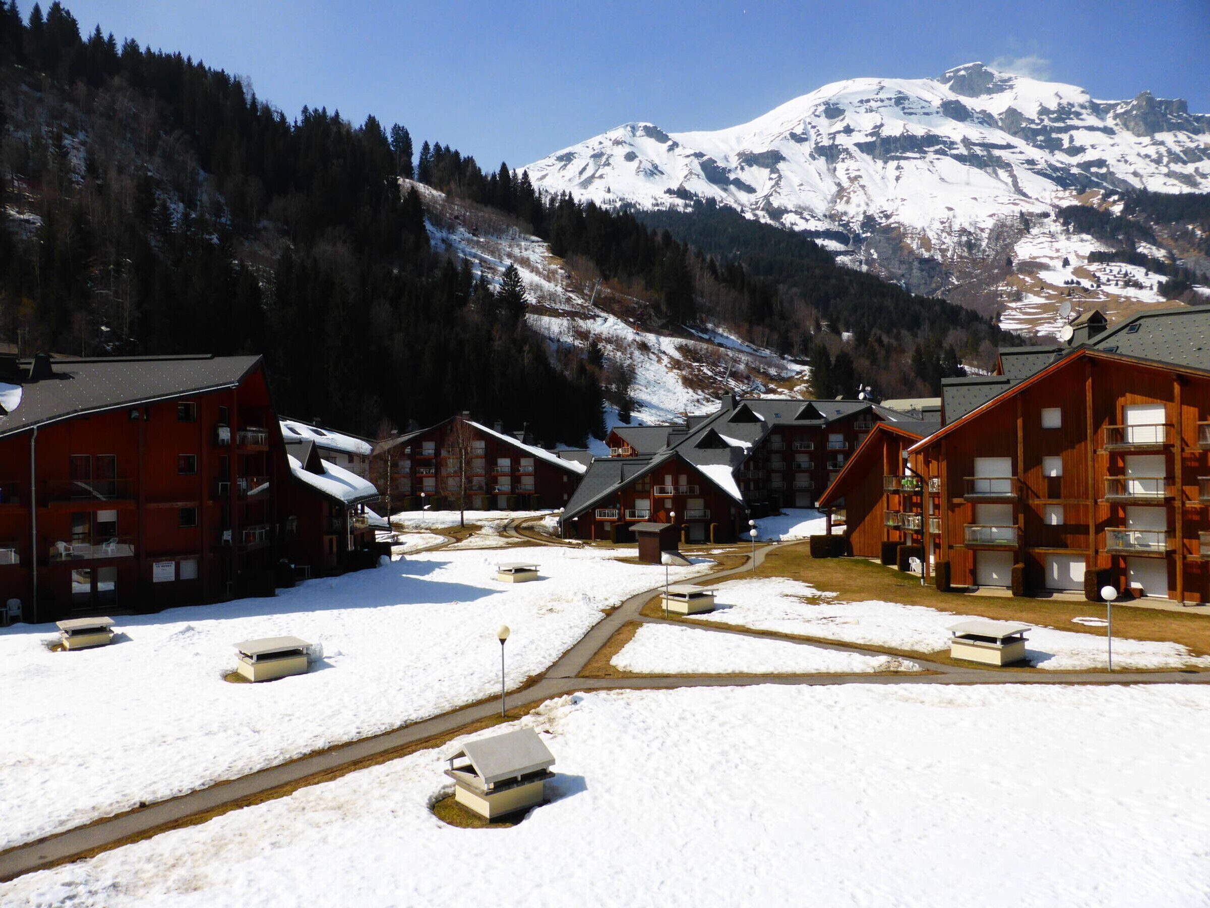 A snow-covered village with wooden buildings and a mountain in the background.