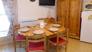 Un comedor con una mesa de madera, sillas y un televisor montado en la pared.