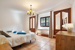 Un dormitorio con cama, mesita de noche, lámpara y vistas al exterior.