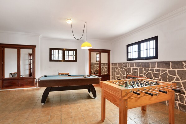 Een kamer met een pooltafel, een tafelvoetbaltafel en een stenen muur.