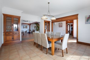 A dining area with a wooden table and chairs, a chandelier, and a cabinet with glass doors.