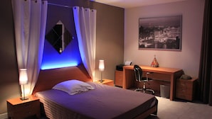 A hotel room with a bed, a desk, a chair, and a picture of a cityscape. - Near beach villa 10p with pool le lavandou (Le Lavandou)