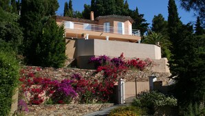 A two-story house with a balcony, surrounded by lush greenery and flowering plants. - Near beach villa 10p with pool le lavandou (Le Lavandou)