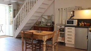 Eine Küche mit Holztisch und -stühlen, einer Mikrowelle und einem Kühlschrank.