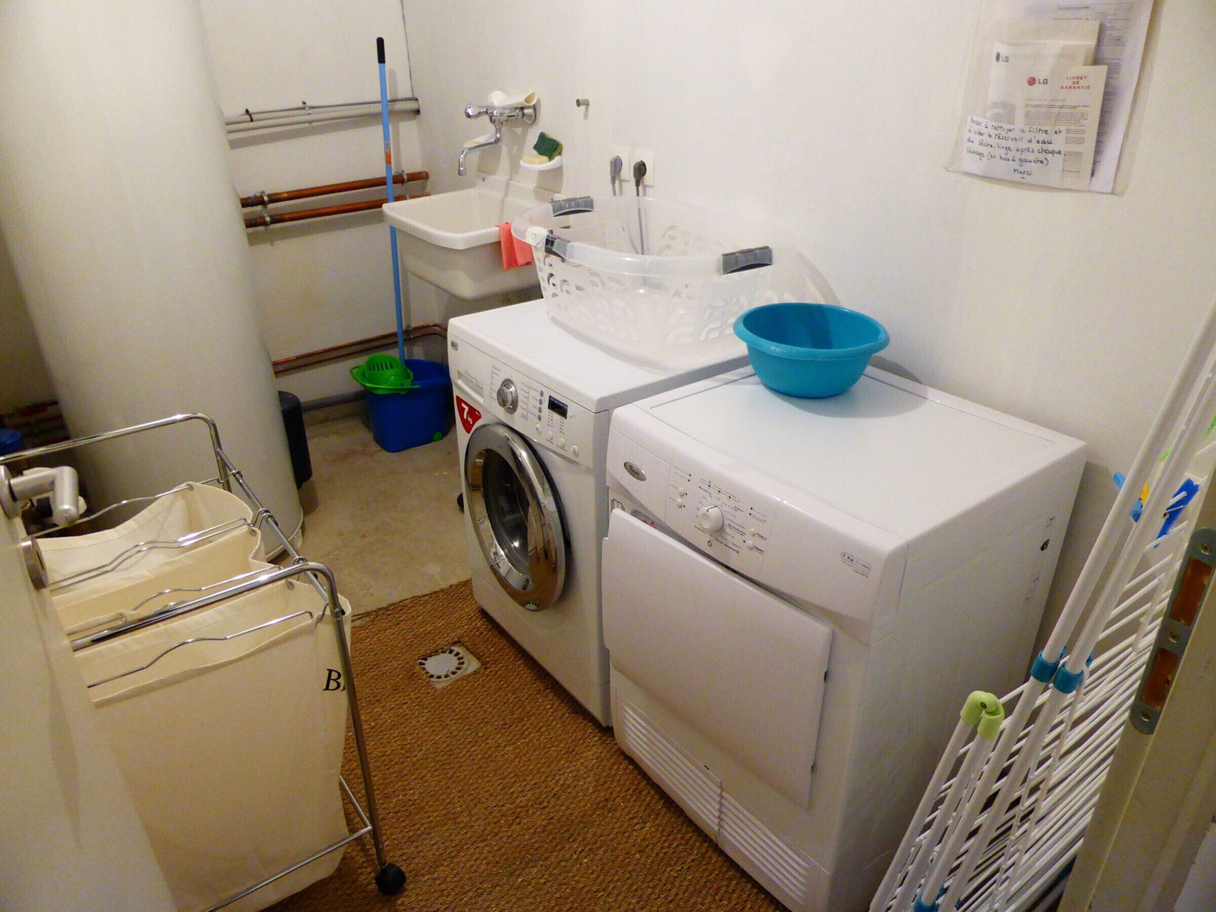 A compact laundry room with a washing machine, dryer, and a small sink.