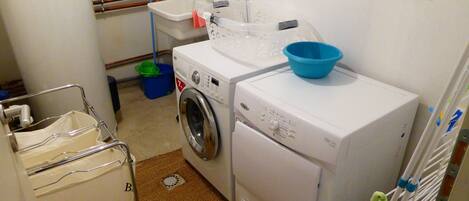 A compact laundry room with a washing machine, dryer, and a small sink.