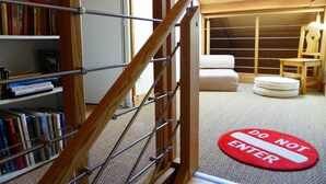 A room with a wooden staircase, a bookshelf filled with books, a 'DO NOT ENTER' mat, a bed, and a chair. - Chalet for 8 pers. with large terrace and parking (Les Contamines-Montjoie)
