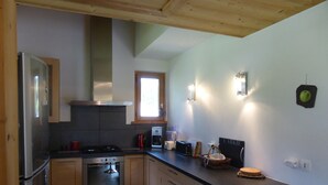 A modern kitchen with wooden cabinets, a built-in oven, a stove, and a window providing natural light. - Chalet for 8 pers. with large terrace and parking (Les Contamines-Montjoie)