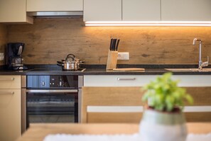 Una cocina moderna con protector de salpicadero de madera, una cafetera, un juego de cuchillos y una planta en maceta.