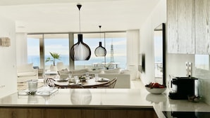Een moderne keuken met een centraal eiland, een eetgedeelte met uitzicht en een groot raam met zicht op de oceaan.