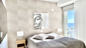 Een moderne slaapkamer met een groot bed, een structuurwand, uitzicht over de stad en een minimalistisch design.