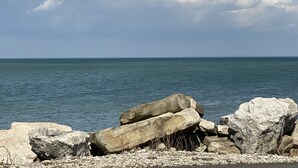 A rocky shoreline with large boulders and calm sea under a partly cloudy sky. - Waterfront Marina View Condo - Walk to Jet Express & Downtown Port Clinton (Port Clinton)