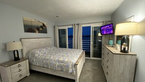 A bedroom with a bed, nightstands, a dresser, a TV, and a balcony with a view. - Waterfront Marina View Condo - Walk to Jet Express & Downtown Port Clinton (Port Clinton)