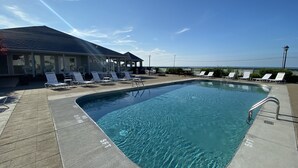 A swimming pool with lounge chairs, a covered seating area, and a building with a sloped roof. - Waterfront Marina View Condo - Walk to Jet Express & Downtown Port Clinton (Port Clinton)