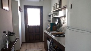 A compact kitchen with a wooden door, a stove, and a refrigerator. - Petrino1880 Sea-vacation Apartment in Chalkidiki (Sithonia)