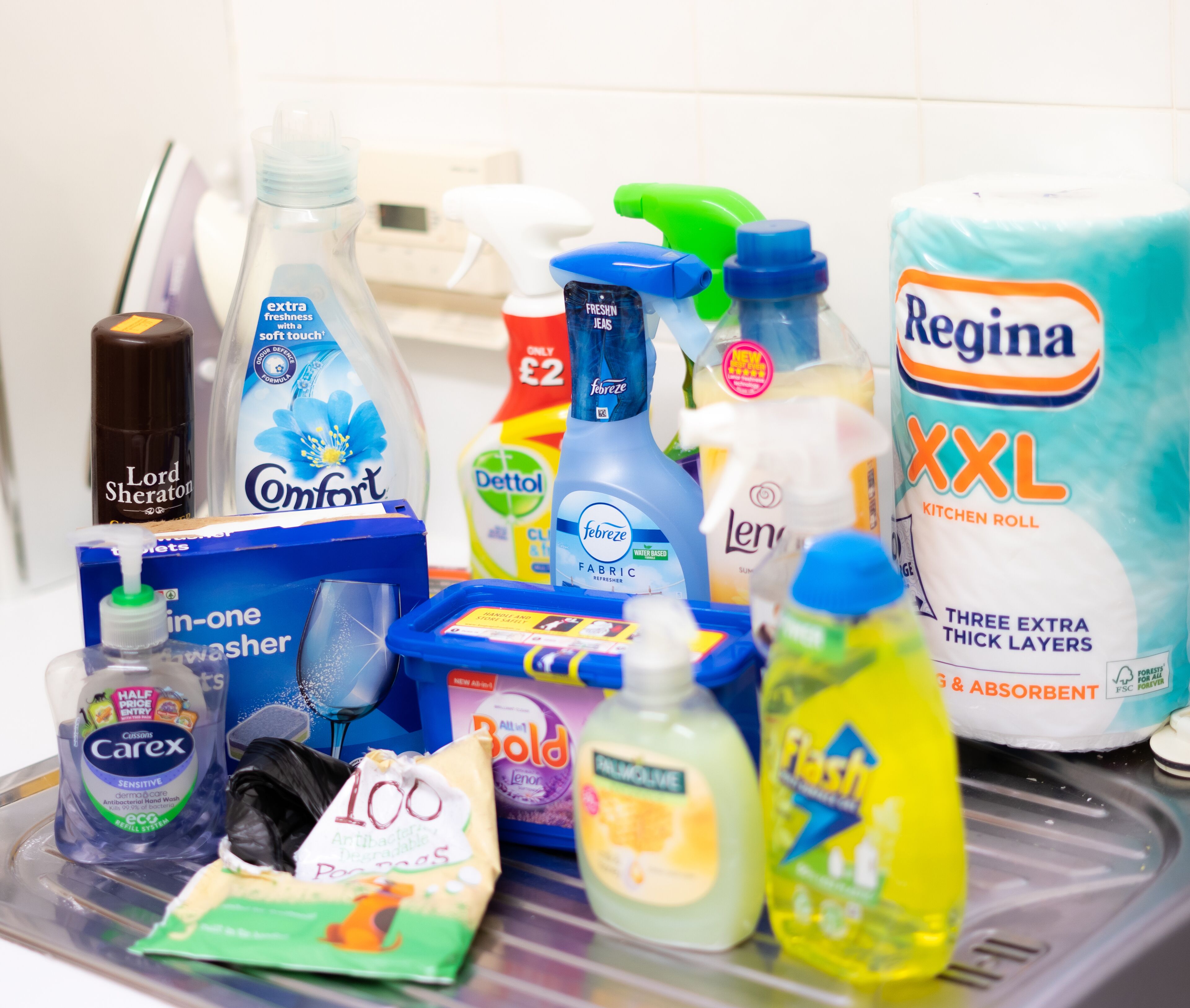 A variety of cleaning supplies including a bottle of Febreze, a pack of Regina XXL kitchen roll, and a bottle of Carex sensitive hand wash.