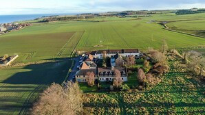 A large, single-story house with a driveway and a small parking area. - Osborne Steading (St. Andrews)