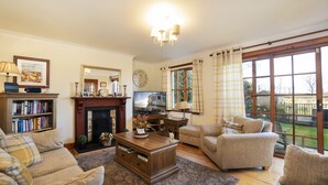 A cozy living room with a fireplace, a television, and comfortable seating. - Osborne Steading (St. Andrews)