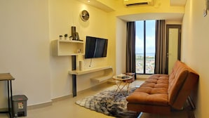 A modern living room with a sofa, TV, and a view of a cityscape through large windows. - Lovina at Pollux Meisterstadt (Batam)