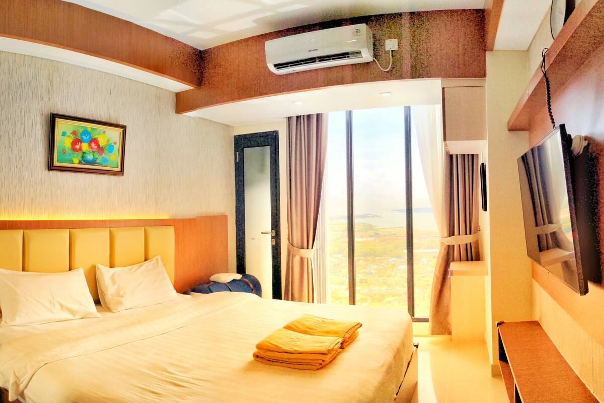 Une chambre d’hôtel avec un lit, une télévision, un appareil de climatisation et un tableau au mur.