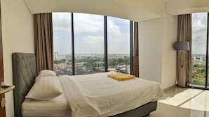 A modern hotel room with a large bed, a view of the city, and a lamp by the window. - Lovina at Pollux Meisterstadt (Batam)