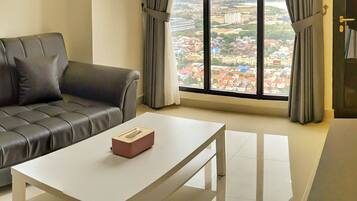 Una sala de estar moderna con un sofá de cuero, una mesa de centro blanca y vistas a un paisaje urbano a través de amplios ventanales.