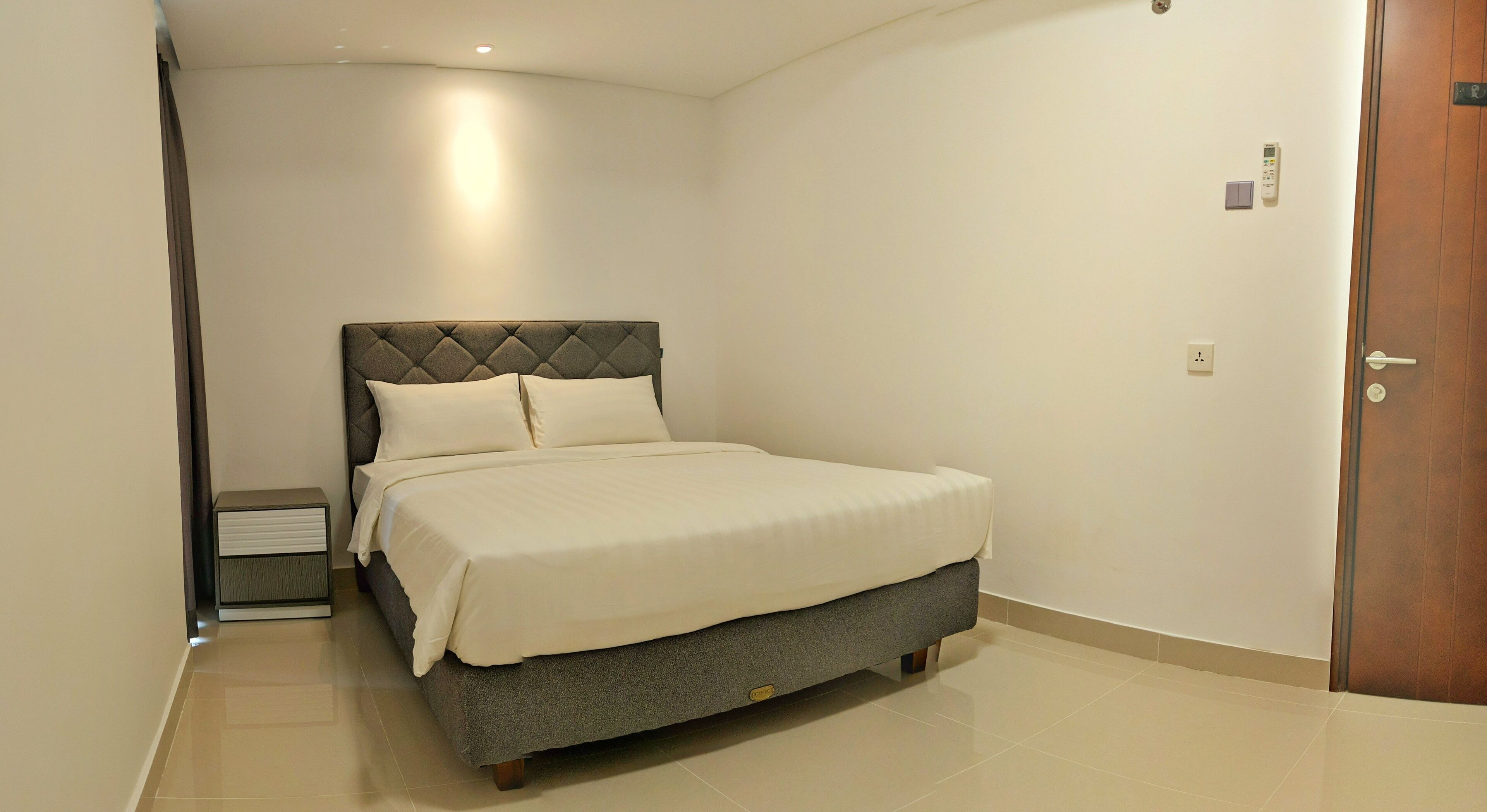 A neatly arranged bedroom with a bed, bedside table, and a door.