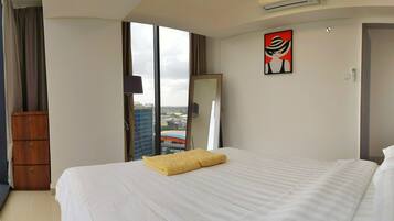 A hotel room with a large bed, a wooden wardrobe, a mirror, and a city view.