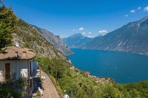 A mountain house with a terrace overlooking a lake and mountains.