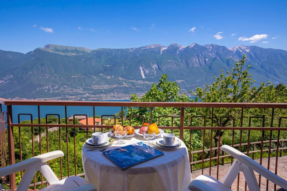 A table with breakfast items and a menu, set against a mountain backdrop.