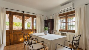 Un comedor con una mesa y sillas, una planta en maceta y vistas a través de ventanas amplias.
