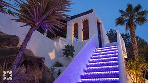 A building with a white exterior, a staircase with purple lighting, and palm trees. - Villa INFINIDAD by Abahana Villas (Moraira)