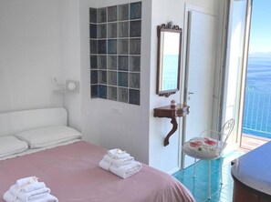 A bedroom with a bed, a mirror, a small table, and a chair.