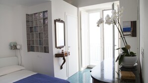 A bedroom with a bed, a dresser, a mirror, a window, and a door. - 2 Bed Flat - Sleeps 4 - Parking - Wifi (Ravello)