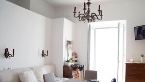 A dining area with a table set for two, a sofa, and a chandelier. - 2 Bed Flat - Sleeps 4 - Parking - Wifi (Ravello)
