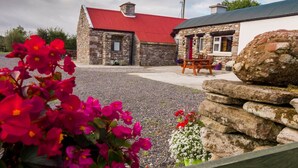 A stone building with a red roof, a wooden bench, and a gravel driveway.