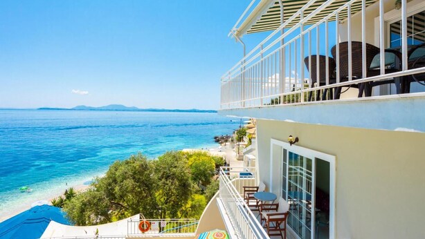 Um hotel com varanda com vista para a praia e o mar.