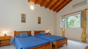 Quarto com duas camas de madeira, uma janela com cortinas e luminárias fixadas na parede.