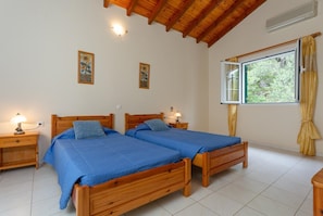 Une chambre avec deux lits en bois, une fenêtre avec des rideaux et des lampes fixées au mur.