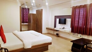 A hotel room with a bed, a TV, a desk, and a wardrobe.